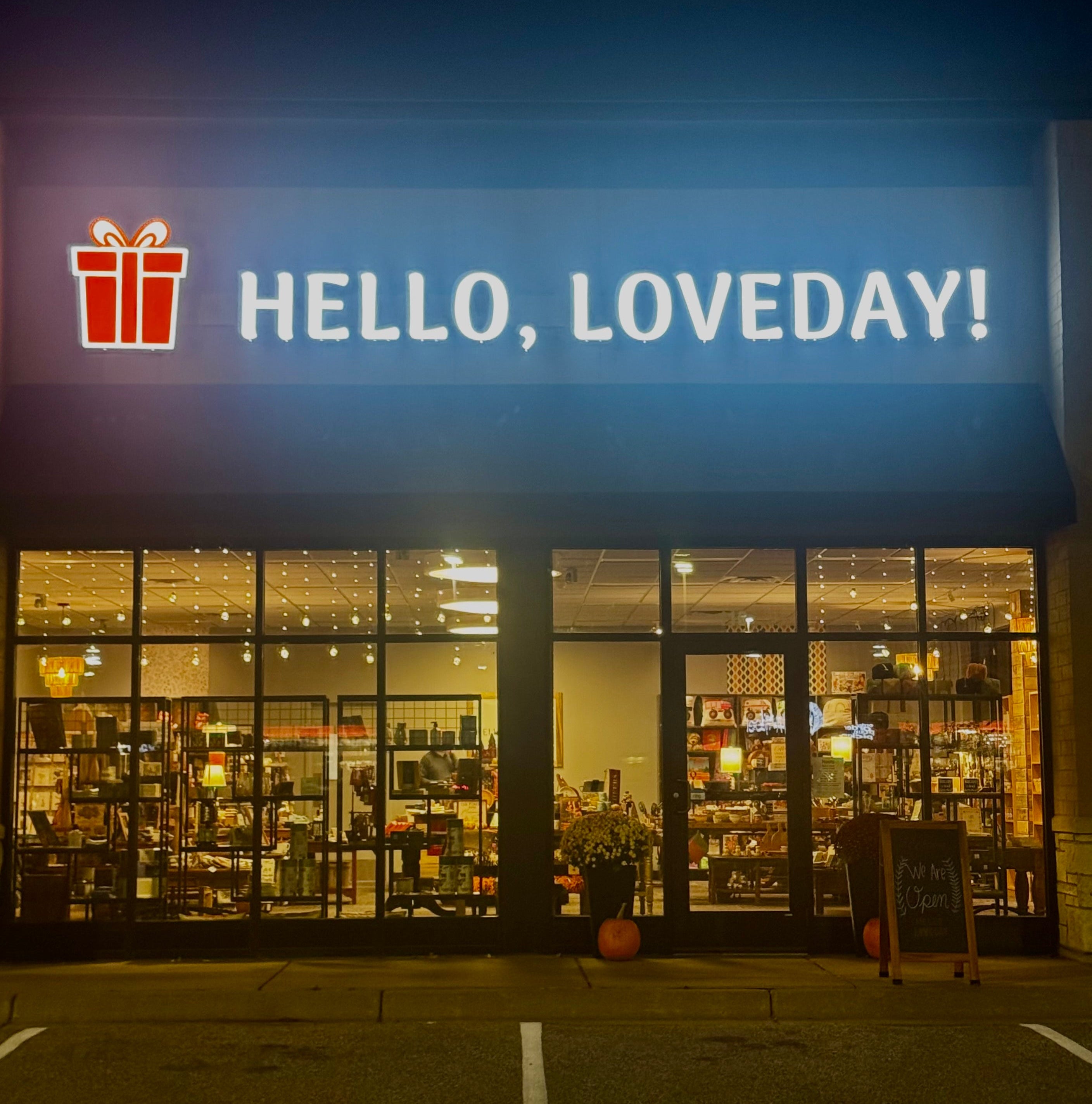 Storefront with 'HELLO, LOVEDAY!' sign and gift icon at night